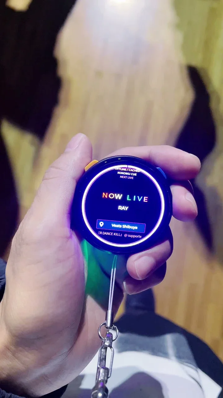 Kokoiku Cueの実機画面。NOW LIVEとRAYの文字を、明るい紫色のリングが囲んでいる